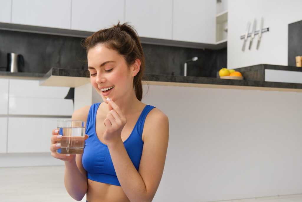 portrait-healthy-smiling-young-woman-taking-vitamins-after-workout-holding-glass-water-1024x683 Como a suplementação ajuda na nutrição esportiva e estética?